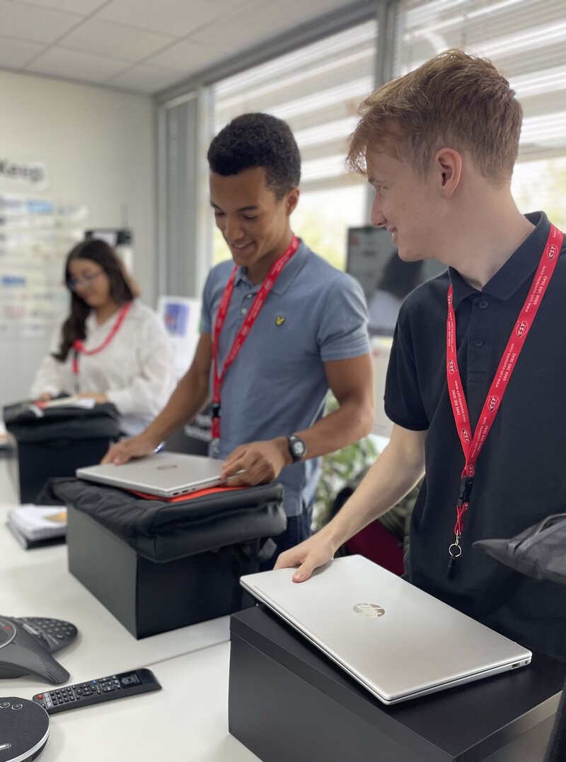 3 young people smiling and looking at laptops in front of them
